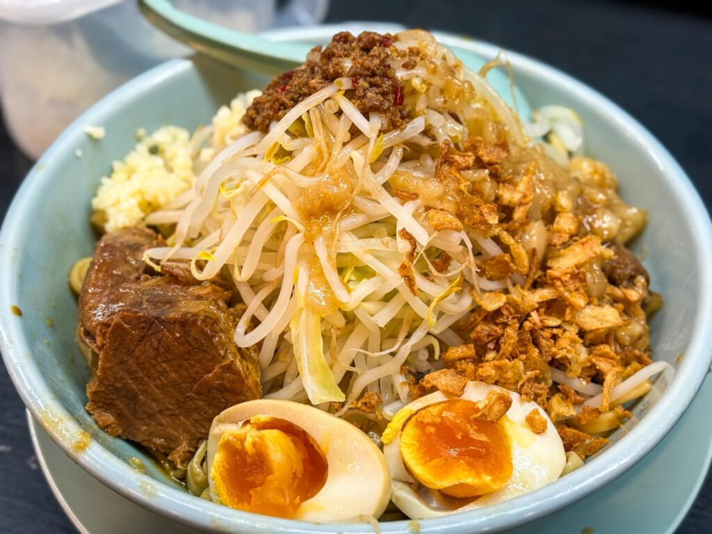 もやしやチャーシュー、味玉が山盛りにトッピングされた汁なし豚そば（大盛り）