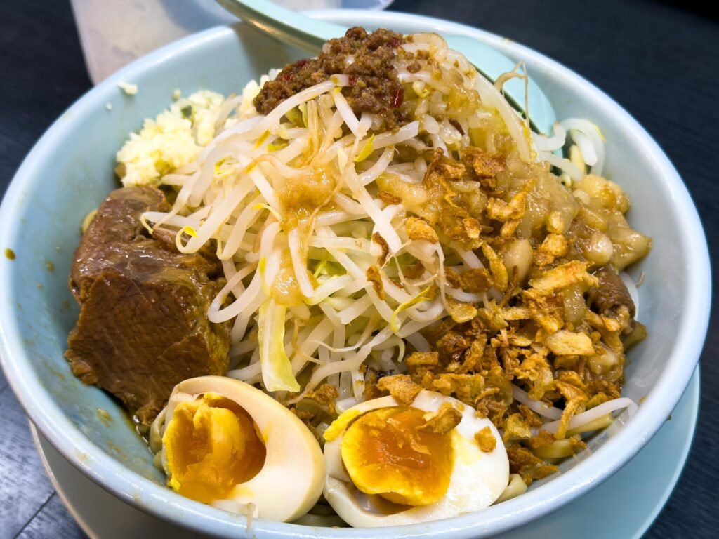 もやしやチャーシュー、味玉が山盛りにトッピングされた汁なし豚そば（大盛り）