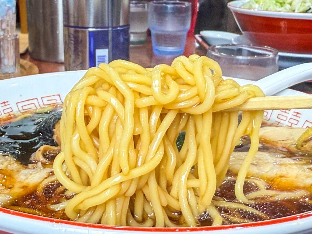壱八商店の中太ストレート麺。スープをたっぷり絡ませ、モチモチ食感が伝わる一枚。