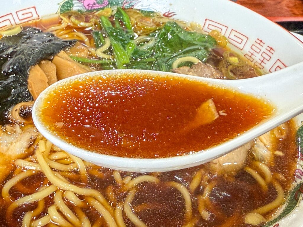 南魚沼「壱八商店」の生姜醤油スープ。レンゲにすくわれた琥珀色のスープは、生姜の香りと醤油のコクが際立つ。