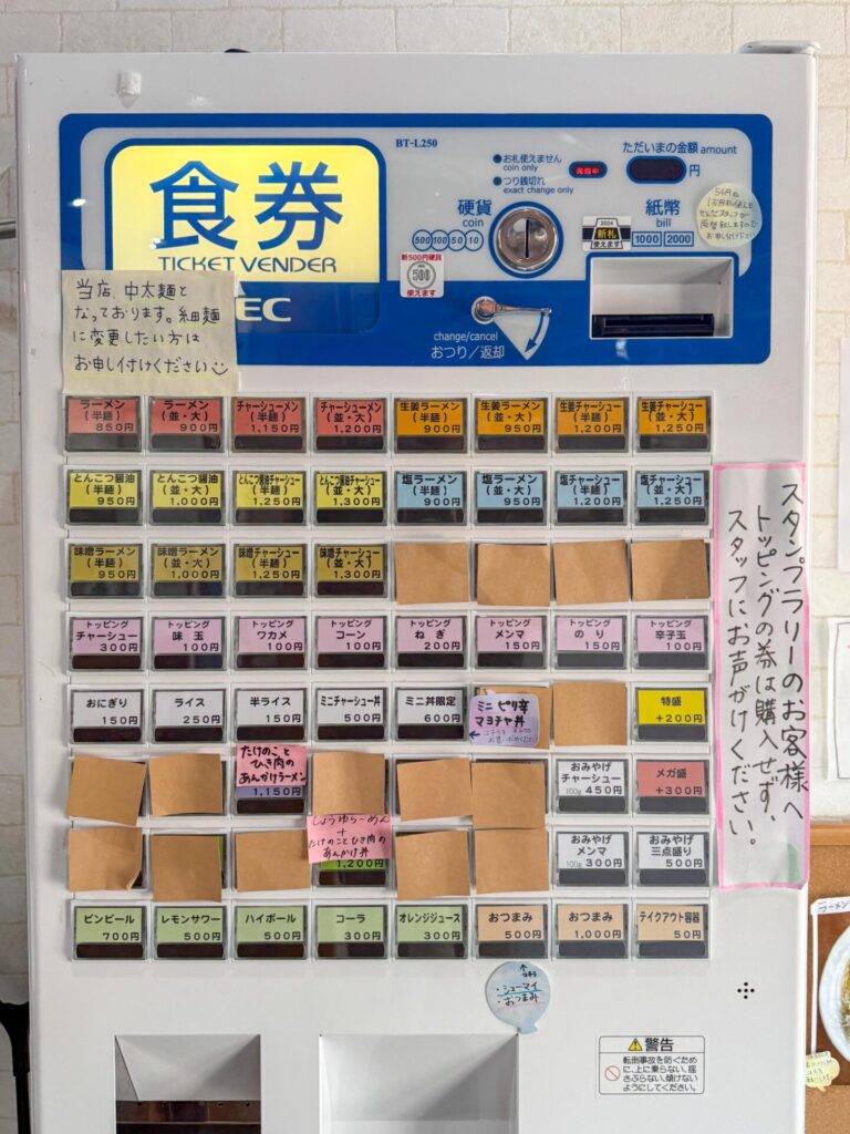 券売機の写真：牧之通りのラーメン屋の券売機。多彩なラーメンとトッピングが並ぶ