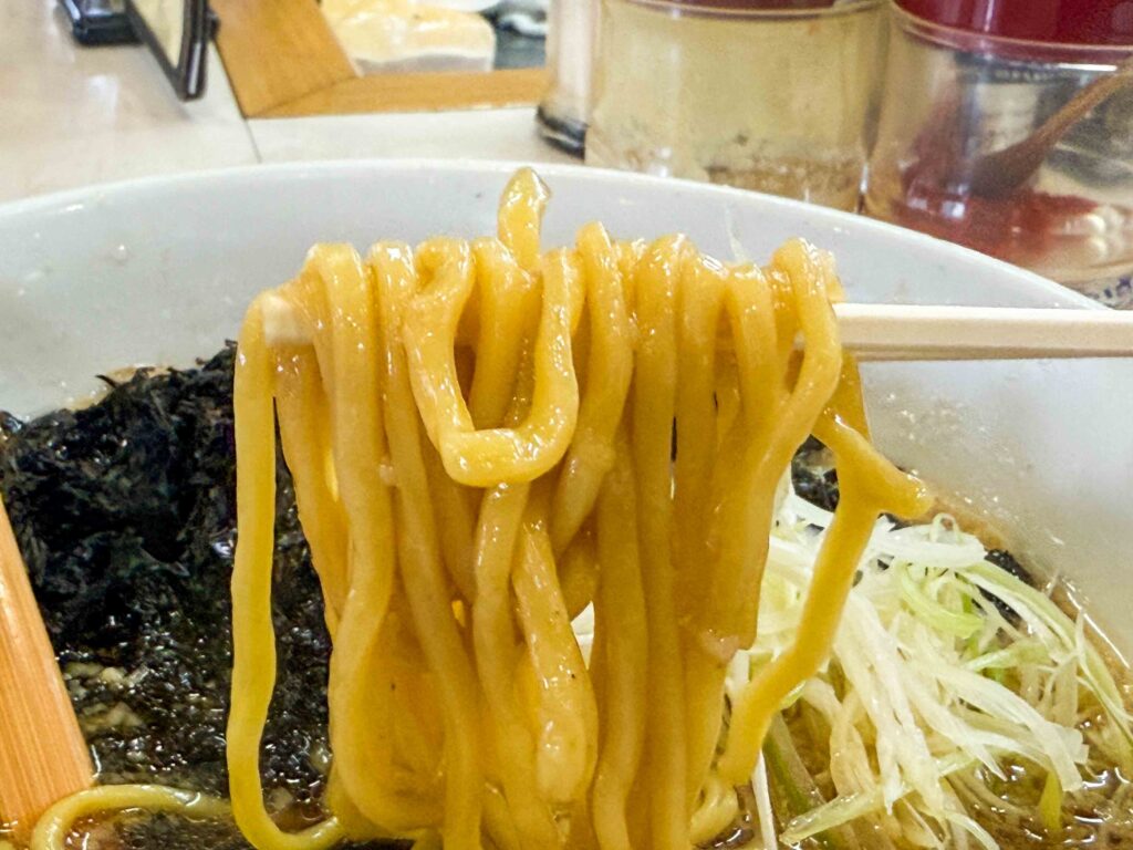 背脂醤油スープをまとった中太麺を持ち上げる瞬間（まつや食堂）