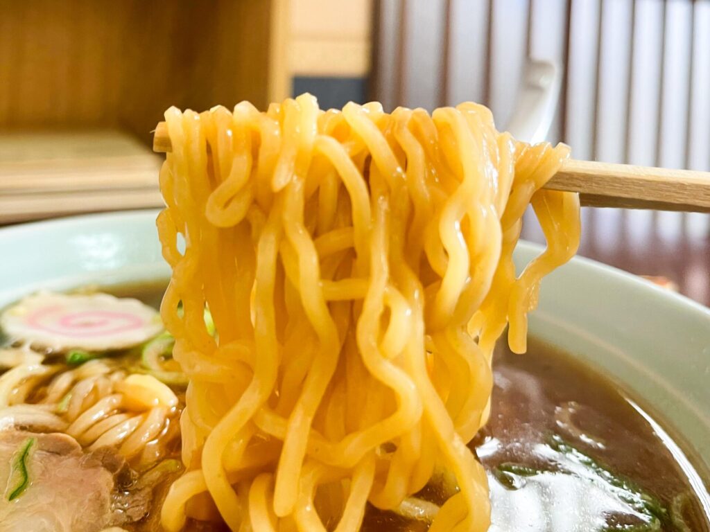 中太ちぢれ麺を箸ですくい上げたラーメンのアップ