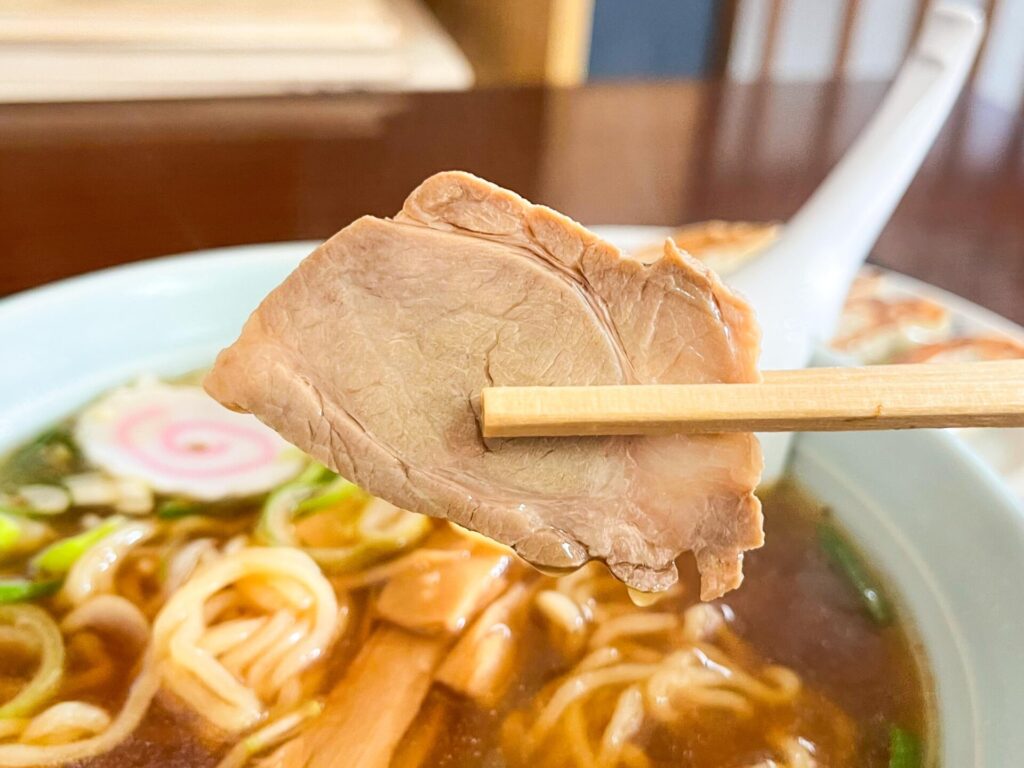 しっとりやわらかいチャーシューを箸で持ち上げた様子