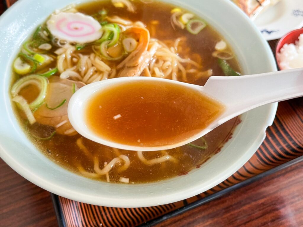 透き通った醤油ベースのスープをすくったレンゲ