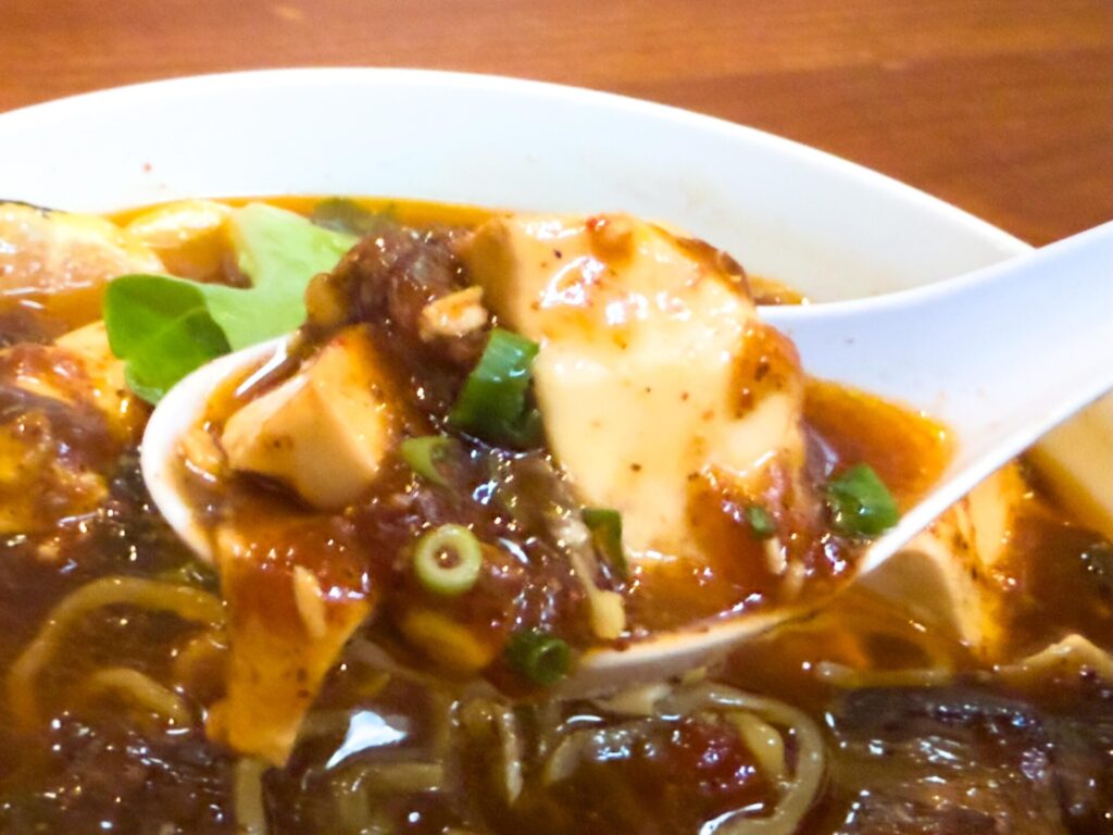 	【麻婆豆腐アップ】とろりとした豆腐と濃厚な麻婆餡がレンゲにのる。