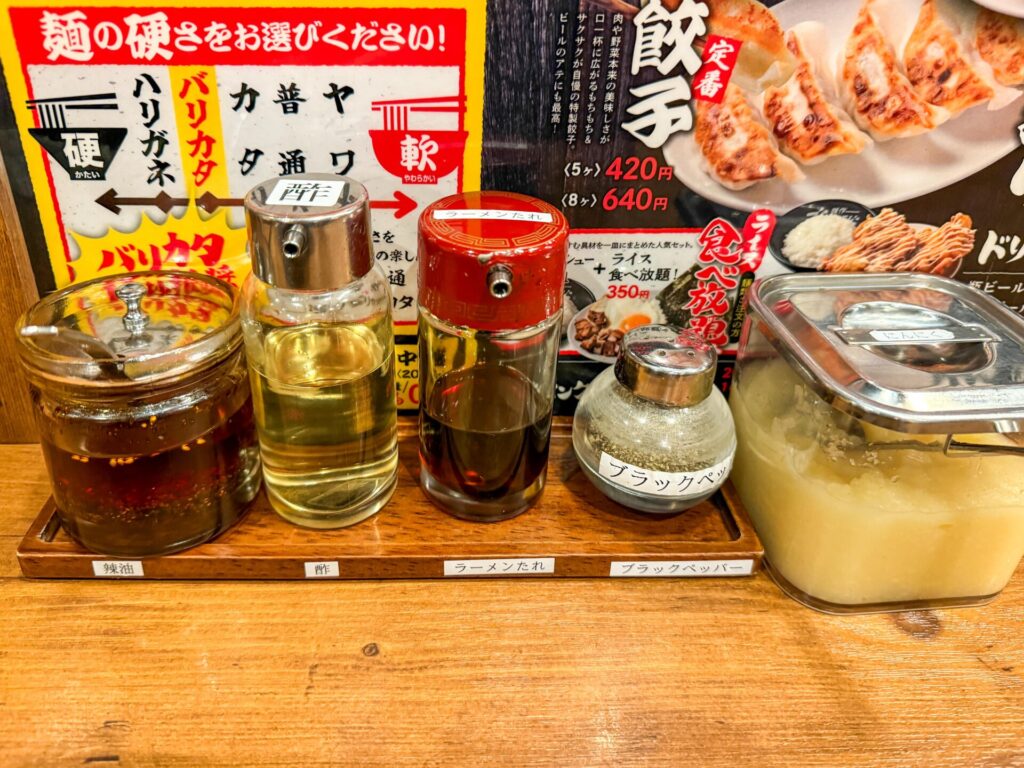 卓上に並ぶ調味料セット。酢・ラー油・ラーメンだれ・ブラックペッパー・刻みにんにくなどが用意されている。